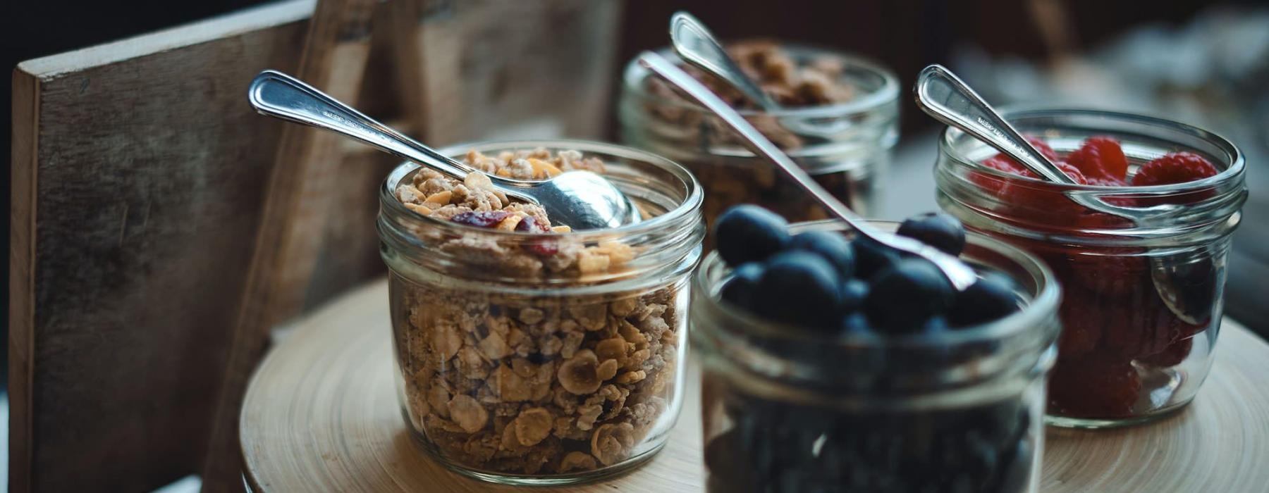granola and fruit filled jars with spoons on a table